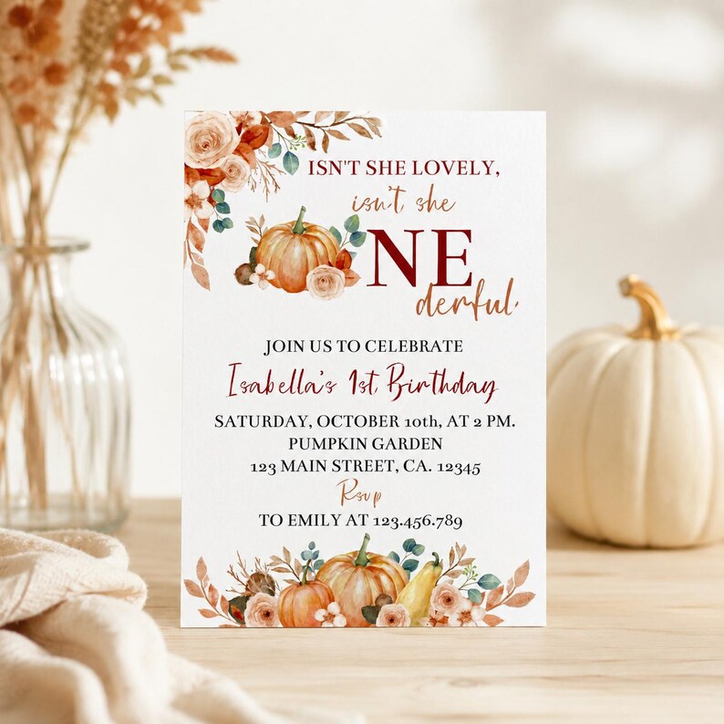 May include: A white rectangular birthday invitation card featuring watercolour illustrations of orange pumpkins, autumn leaves, and flowers. The text reads: ISN'T SHE LOVELY, isn't she ONEderful, JOIN US TO CELEBRATE Isabella's 1st Birthday, OCTOBER 10th, AT 2 PM.