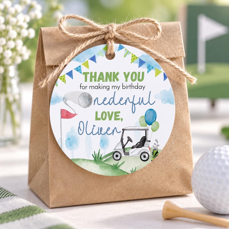 May include: A round paper gift tag tied with twine to a brown paper bag. The tag features a watercolor golf theme with a golf cart, balloons, and bunting. Text reads: THANK YOU for making my birthday onederful LOVE, Oliver, with a golf flag graphic.