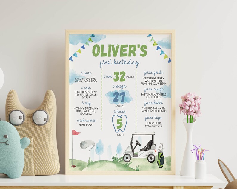 May include: A green and blue illustrated first birthday poster for a boy named Oliver. The poster features a golf buggy, a golf ball, and a golf flag. It includes details about Oliver's height, weight, and number of teeth. The poster also lists Oliver's favourite foods, songs, books, and toys.