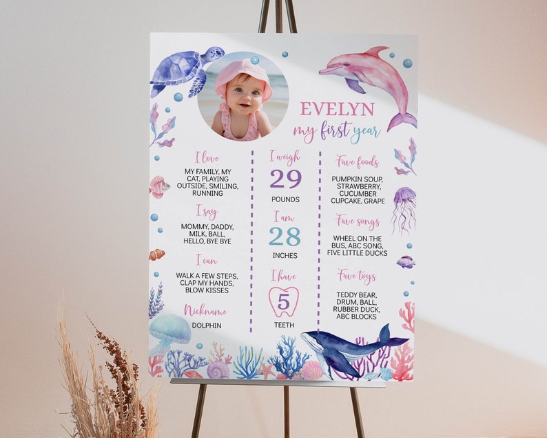 May include: A white milestone poster featuring a circular photo of a baby, watercolour sea creatures including a turtle, dolphin, and whale, and text detailing personal facts like 29 pounds, 28 inches, and 5 teeth, with pink and blue accents.