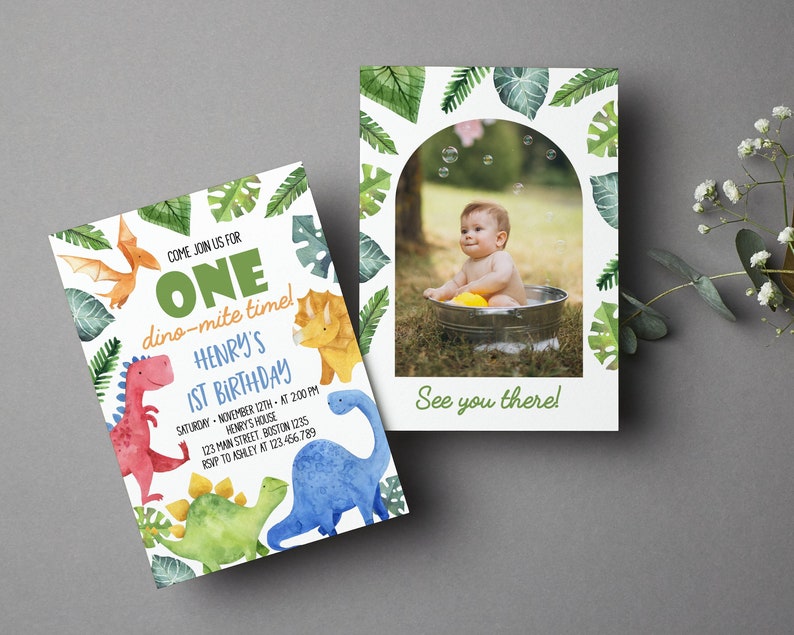 May include: Two rectangular birthday invitation cards featuring watercolor dinosaur illustrations and green tropical leaves. The left card displays text including ONE, dino-mite time!, HENRY'S 1ST BIRTHDAY, and event details. The right card features an arched photo frame with a child in a tub and the text See you there!.