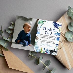 May include: A rectangular thank you card featuring a photograph of a toddler in a blue outfit on the left and watercolor sea life illustrations on the right. The text reads: THANK YOU. Thank you so much for celebrating my birthday with me and for the wonderful present you gave me! I had such a good time playing with all my friends and eating cake! Love, Huson.
