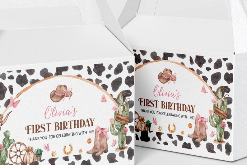 May include: Two white cardboard favor boxes featuring a cow print pattern and a watercolor design with a brown cowboy hat, pink bows, a cactus, a horseshoe, and a money bag. The text reads Olivia's FIRST BIRTHDAY THANK YOU FOR CELEBRATING WITH ME!