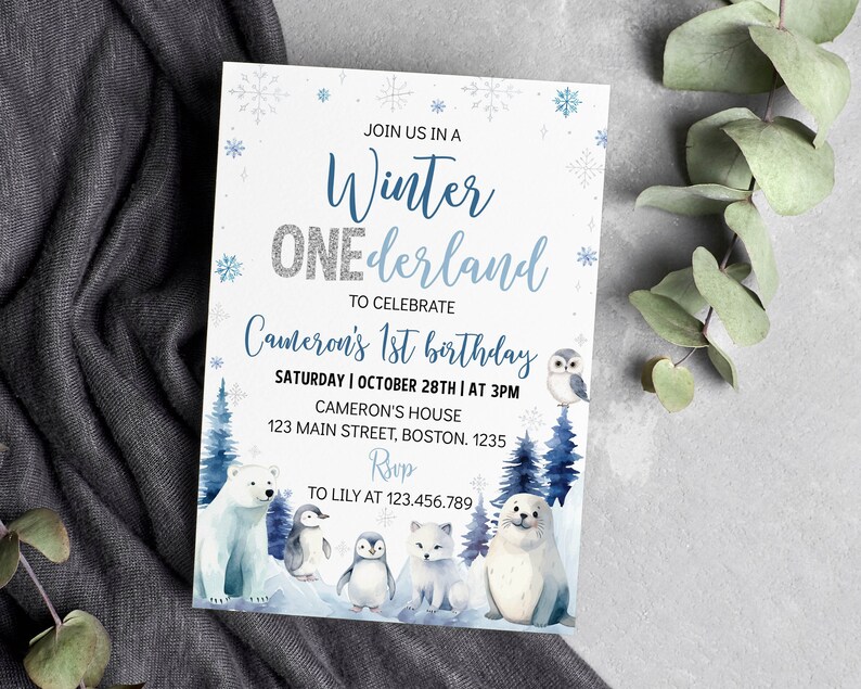 May include: A rectangular invitation card with a white background featuring blue snowflakes and the text "JOIN US IN A Winter ONEderland TO CELEBRATE Cameron's 1st birthday". It includes illustrations of a polar bear, penguins, and a seal.