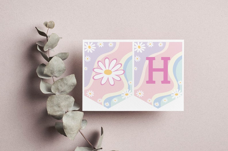 May include: Two rectangular pennant flags featuring a pastel wavy background of pink, lavender, and light blue. The left flag displays a large white daisy with a yellow center, while the right flag features a bold, solid pink capital letter H.