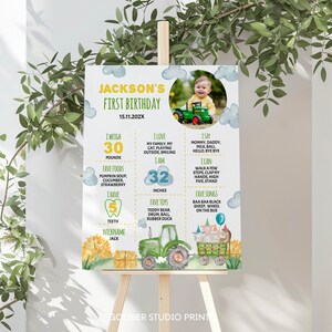 May include: A colorful first birthday poster for a boy named Jackson. The poster features a tractor, farm animals, and a photo of the birthday boy. It includes details about his age, weight, height, favorite foods, toys, and songs. The poster is decorated with clouds, sunflowers, and hay bales.