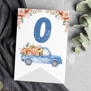 May include: A white rectangular card featuring a large blue number zero at the top, decorated with watercolour orange pumpkins and foliage in the bed of a blue pickup truck, with additional floral accents in the top corners of the card.