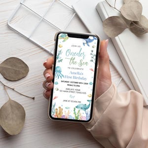Puede incluir: Una invitaci&oacute;n digital azul y verde para una fiesta de primer cumplea&ntilde;os con el texto "Oneder the Sea" y una ilustraci&oacute;n de acuarela de una ballena, una medusa y tortugas marinas. La invitaci&oacute;n incluye la fecha, la hora y la ubicaci&oacute;n de la fiesta.