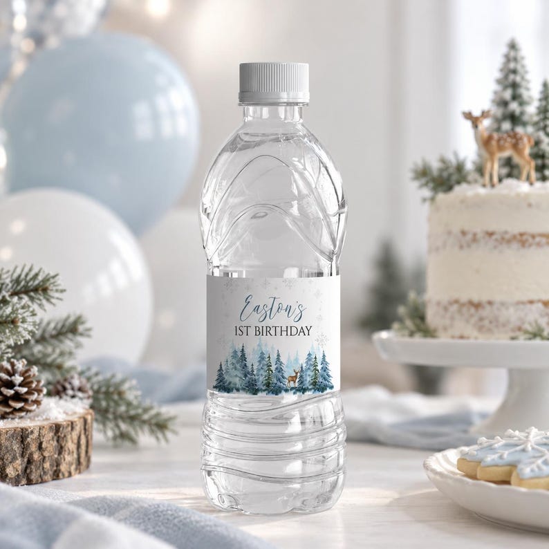 May include: A clear plastic water bottle with a white cap and a custom label. The label features a blue and white winter forest scene with a small deer, snowflakes, and the text Easton's 1ST BIRTHDAY in a dark blue script and print font.