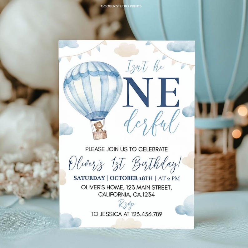 Pu&ograve; includere: Un biglietto d'invito per compleanno con un'illustrazione ad acquerello di una mongolfiera azzurra con un orsacchiotto nel cesto. Il testo recita: Isn't he ONEderful, PLEASE JOIN US TO CELEBRATE Oliver's 1st Birthday! SATURDAY | OCTOBER 18TH | AT 2 PM.