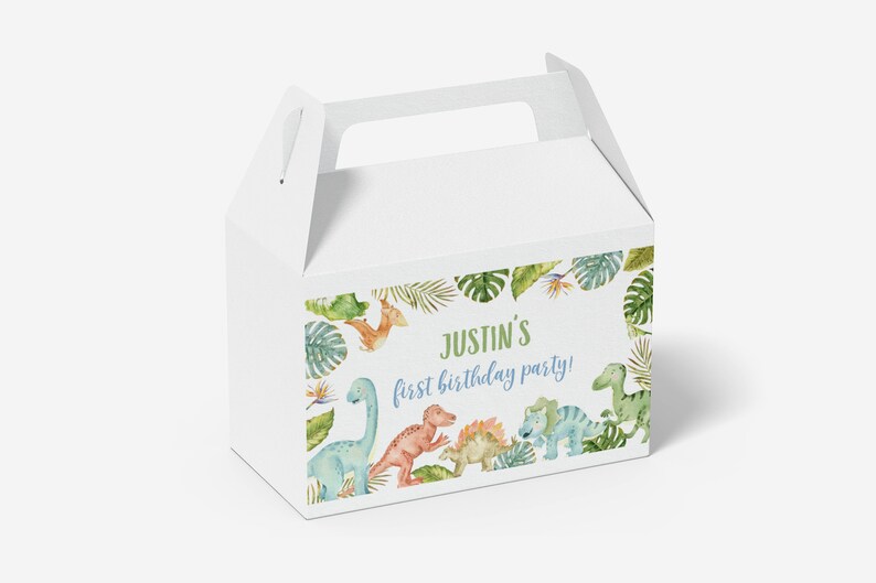 May include: A white cardboard gable box featuring a colorful watercolor illustration of various dinosaurs and tropical leaves. The text on the front reads Justin's first birthday party! in green and blue script and block lettering.