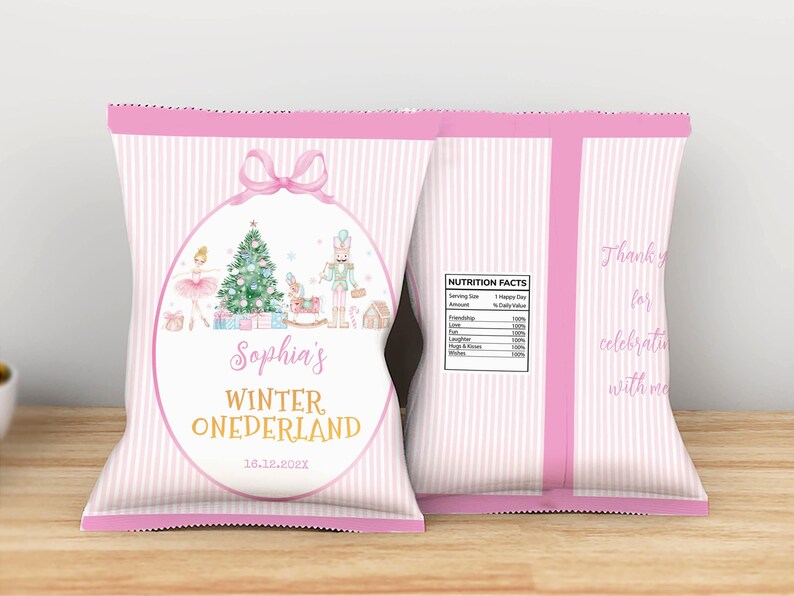 May include: A pink and white striped snack bag featuring a central oval frame with a pink bow. Inside the frame is a Christmas tree, a ballerina, and a nutcracker. Text reads Sophia's WINTER ONEDERLAND 16.12.202X. The back includes a nutrition facts label.