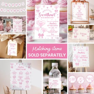 May include: Pink and white first birthday party decorations with a watercolor heart balloon theme. The set includes a banner, invitation, thank you tags, water bottle labels, cupcake toppers, and signs. The text on the invitation reads "Our Little Sweetheart is Turning One!" and includes the birthday girl's name, date, time, and location. The text on the sign reads "Welcome to Amelia's First Birthday Party".