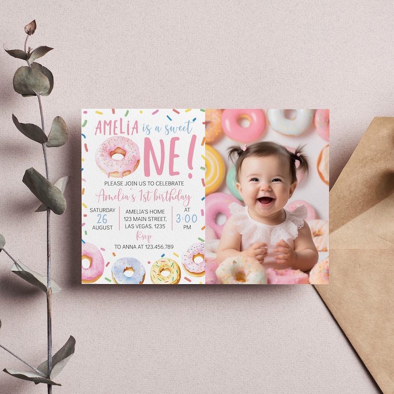 May include: A pink and white donut with sprinkles is on a white background with the text "Amelia is a sweet one!" and a photo of a baby girl. The text also says "Please join us to celebrate Amelia's 1st birthday" and includes the date, time, and location of the party.