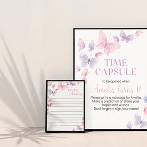 May include: Two framed prints with butterfly designs. The larger print reads "TIME CAPSULE" and "Amelia turns 18." The smaller print has lined space for a message. Both prints feature watercolor butterflies in pink and purple.