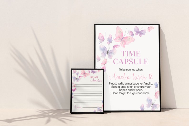 May include: Two framed prints with butterfly designs. The larger print reads "TIME CAPSULE" and "Amelia turns 18." The smaller print has lined space for a message. Both prints feature watercolor butterflies in pink and purple.