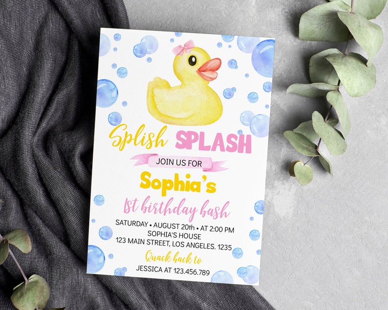 May include: A rectangular birthday invitation card featuring a yellow rubber duck with a pink bow, surrounded by blue watercolor bubbles. The text reads Splish Splash, Join us for Sophia's 1st birthday bash, Saturday August 20th at 2:00 PM, Sophia's house, 123 Main Street, Los Angeles, 1235, Quack back to Jessica at 123.456.789.