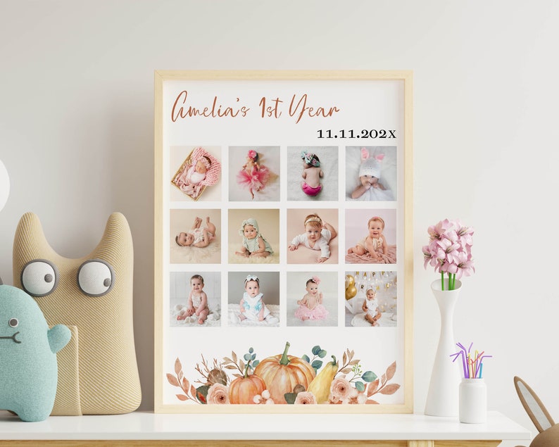 May include: A framed photo collage print titled Amelia's 1st Year with the date 11.11.202x. The poster features twelve square photographs of a baby in various outfits and poses, arranged in a grid, with a watercolor pumpkin and floral border.