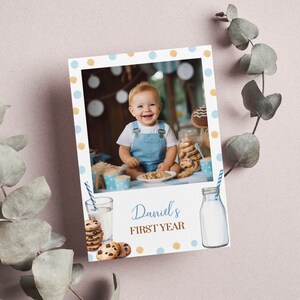 May include: A blue and white polka dot photo card with a picture of a baby boy wearing a blue overall. The card says "Daniel's First Year" and has a picture of a glass of milk and a bottle of milk with cookies.