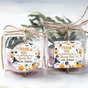 May include: Two clear square boxes tied with twine, each containing a lavender macaron. The boxes have a circular sticker with Halloween-themed illustrations and the text "THANK YOU for making my day a Spooky One! LOVE, JACKSON."