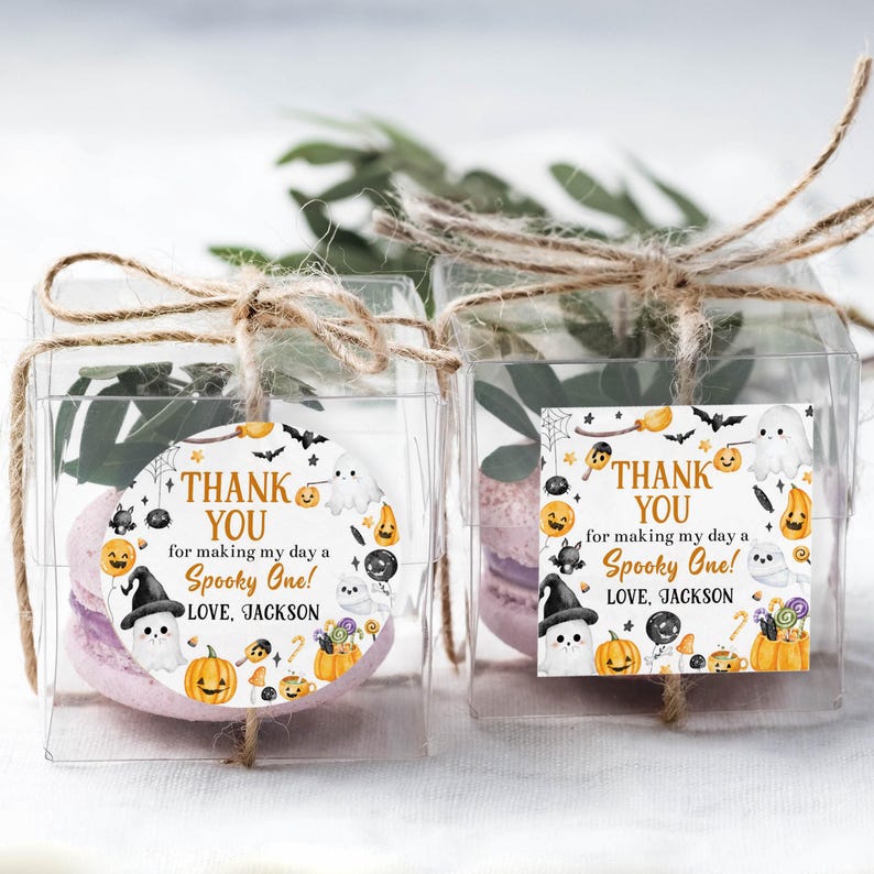 May include: Two clear square boxes tied with twine, each containing a lavender macaron. The boxes have a circular sticker with Halloween-themed illustrations and the text "THANK YOU for making my day a Spooky One! LOVE, JACKSON."