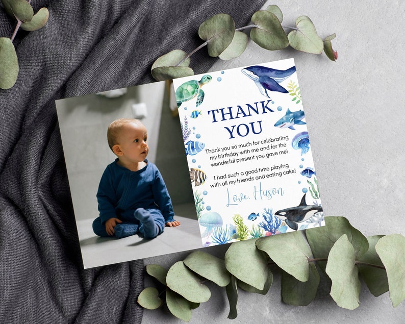 May include: A rectangular thank you card featuring a photograph of a toddler in a blue outfit on the left and a white background with watercolor illustrations of a whale, shark, sea turtle, jellyfish, and coral on the right with the text THANK YOU.