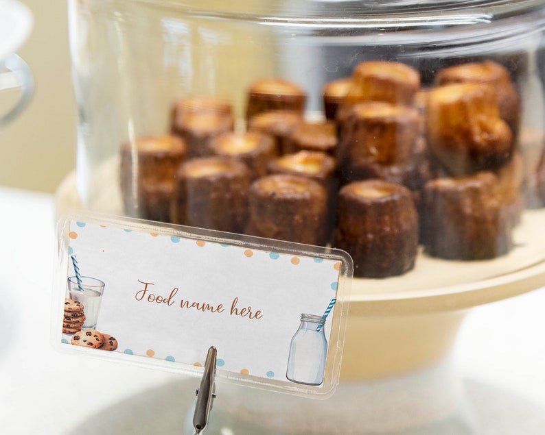 May include: A glass display case filled with small, round, brown pastries. A sign with the text "Food name here" is attached to the front of the case.