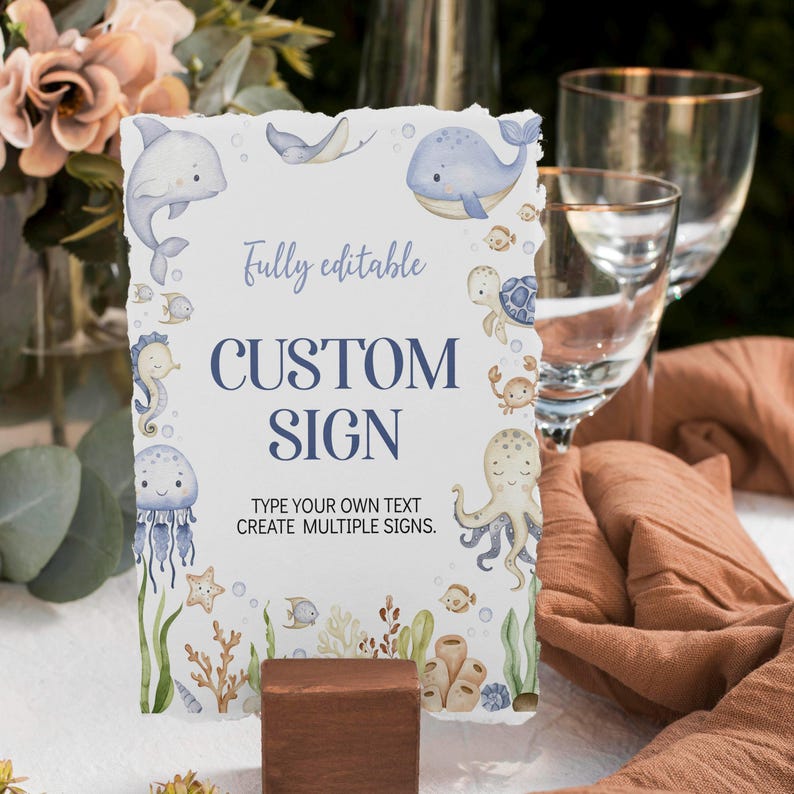 May include: A custom sign with a watercolor ocean theme. The sign features illustrations of marine life, including a whale, dolphin, and octopus. The text on the sign reads "Fully editable CUSTOM SIGN" with space to add your own text. The sign is displayed on a wooden block.