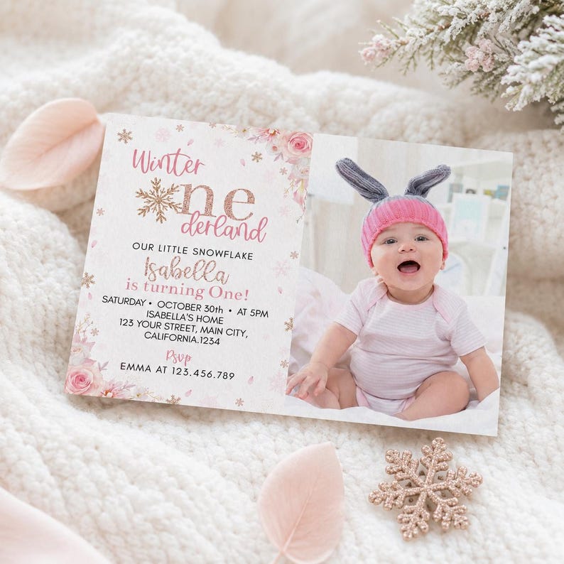May include: A rectangular birthday invitation card featuring a photo of a baby wearing a pink hat with bunny ears. The text reads Winter onederland, Our little snowflake Isabella is turning one, Saturday October 30th at 5pm, and RSVP details.