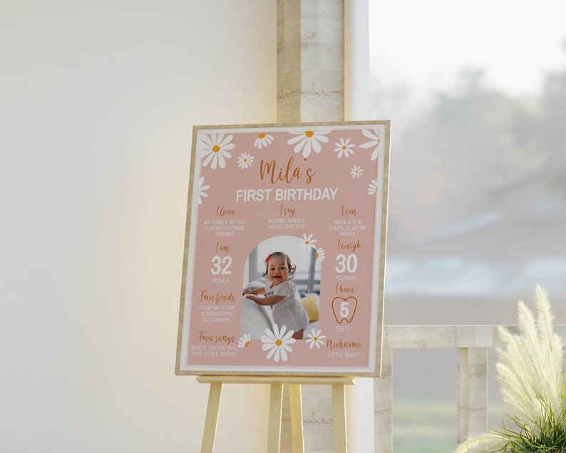 K&ouml;nnte beinhalten: Ein rosa-wei&szlig;es Schild zum ersten Geburtstag mit einem G&auml;nsebl&uuml;mchenrand. Das Schild enth&auml;lt ein Foto eines kleinen M&auml;dchens und Details &uuml;ber ihr erstes Jahr, darunter ihre Gr&ouml;&szlig;e, ihr Gewicht, ihre Lieblingsessen und Lieder. Der Text auf dem Schild lautet "Mila's First Birthday".