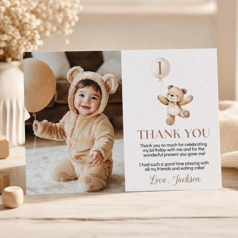 May include: A rectangular thank you card featuring a photo of a child in a tan bear-ear hooded onesie holding a beige balloon. The right side displays a watercolor teddy bear with a balloon, the number 1, and text: Thank you so much for celebrating my birthday with me and for the wonderful present you gave me! I had such a good time playing with all my friends and eating cake! Love, Jackson.