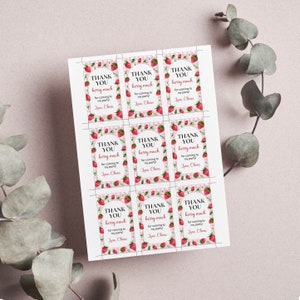 May include: A printable sheet of nine rectangular gift tags featuring a pink and white gingham border decorated with red strawberries. Each tag displays the text THANK YOU berry much for coming to my party! Love, Olivia in black and red font.