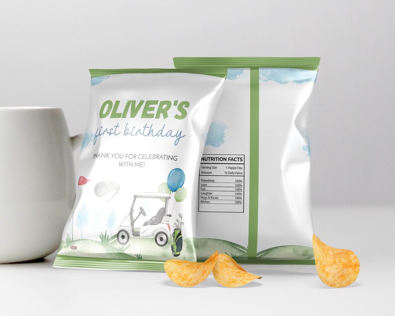 May include: Two white chip bags with a golf theme. The front bag reads "OLIVER'S first birthday" with a golf cart illustration. The back of the bag has a nutrition facts label. A few chips are in front of the bags.