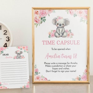 K&ouml;nnte beinhalten: Ein goldgerahmtes Schild und eine passende Karte mit einem Aquarell-Koala und rosa Blumen. Das Schild tr&auml;gt die Aufschrift: TIME CAPSULE, To be opened when Amelia turns 18, Please write a message for Amelia. Make a prediction or share your hopes.
