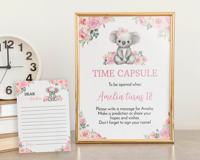 K&ouml;nnte beinhalten: Ein goldgerahmtes Schild und eine passende Karte mit einem Aquarell-Koala und rosa Blumen. Das Schild tr&auml;gt die Aufschrift: TIME CAPSULE, To be opened when Amelia turns 18, Please write a message for Amelia. Make a prediction or share your hopes.