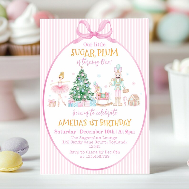 May include: A rectangular birthday invitation card with a pink and white striped background. It features a pink bow at the top, a ballerina, a Christmas tree, a nutcracker, and a rocking horse. Text reads: Our little SUGAR PLUM is turning One! AMELIA'S 1ST BIRTHDAY, Saturday | December 10th | At 2pm, The Sugarplum Lounge, 123 Candy Cane Court, Toyland, 12345, Rsvp to Clara by Dec 8th at 123.456.789.