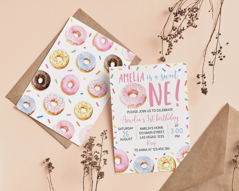 May include: A birthday invitation card and matching envelope liner featuring a watercolor donut pattern with colorful sprinkles. The text reads: AMELIA is a sweet ONE! PLEASE JOIN US TO CELEBRATE Amelia's 1st birthday SATURDAY 26 AUGUST AMELIA'S HOME 123 MAIN STREET, LAS VEGAS. 1235 AT 3:00 PM RSVP TO ANNA AT 123.456.789.