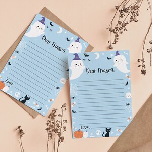 May include: Two light blue stationery sheets with lined writing space, each featuring the printed text Dear Mason and Love. The design includes cartoon ghosts wearing purple hats, black cats, orange pumpkins, white skulls, bats, and spiderwebs.