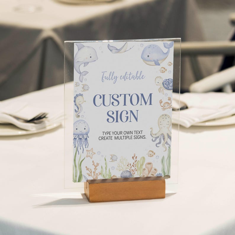 May include: A clear acrylic sign with a wooden base, featuring a watercolor design of marine life. The sign reads "CUSTOM SIGN" with the text "fully editable" and "TYPE YOUR OWN TEXT CREATE MULTIPLE SIGNS."