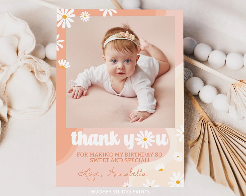 May include: A rectangular thank you card featuring a photo of a baby wearing a floral headband. The card has a peach-colored background with white daisy illustrations and the text: thank you FOR MAKING MY BIRTHDAY SO SWEET AND SPECIAL! Love, Annabella.