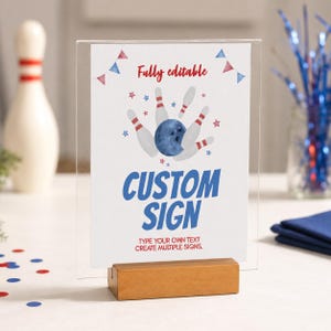 May include: A clear acrylic sign holder with a wooden base displaying a white card with red and blue bowling-themed graphics. The text reads Fully editable, CUSTOM SIGN, and TYPE YOUR OWN TEXT CREATE MULTIPLE SIGNS in red and blue lettering.