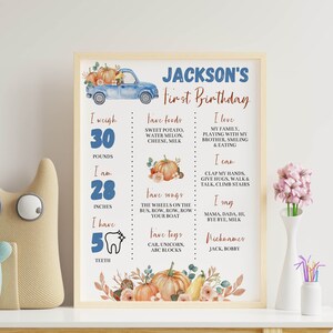 May include: A framed birthday milestone sign for Jackson featuring a blue truck, pumpkins, and text detailing weight in pounds, height in inches, favorite foods, songs, toys, and developmental milestones like teeth count, words, and activities.