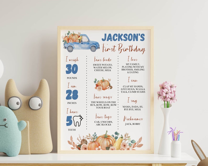 May include: A framed birthday milestone sign for Jackson featuring a blue truck, pumpkins, and text detailing weight in pounds, height in inches, favorite foods, songs, toys, and developmental milestones like teeth count, words, and activities.