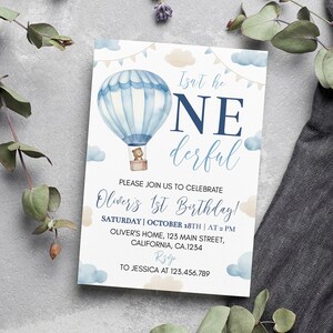 Pu&ograve; includere: Un biglietto d'invito di compleanno rettangolare con un'illustrazione ad acquerello di una mongolfiera blu con un orsacchiotto nel cesto. Il testo recita: Isn't he ONEderful, PLEASE JOIN US TO CELEBRATE Oliver's 1st Birthday! SATURDAY | OCTOBER 18TH | AT 2 PM, OLIVER'S HOME, 123 MAIN STREET, CALIFORNIA, CA.1234, RSVP TO JESSICA AT 123.456.789.
