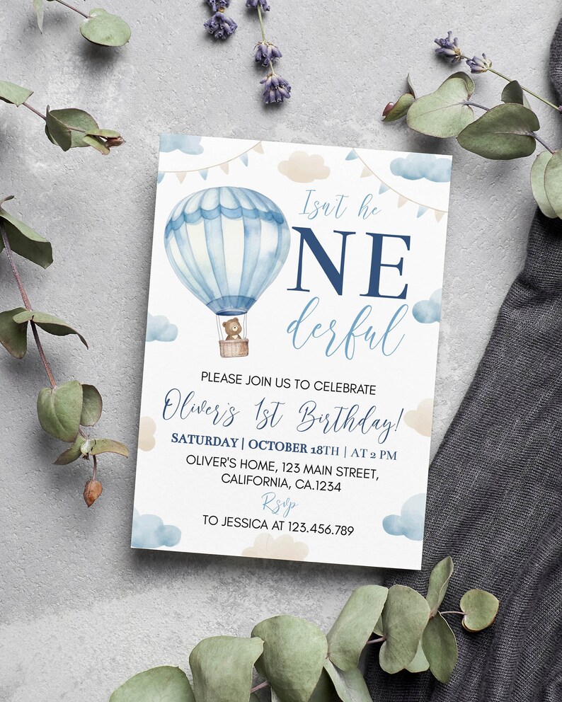 Pu&ograve; includere: Un biglietto d'invito di compleanno rettangolare con un'illustrazione ad acquerello di una mongolfiera blu con un orsacchiotto nel cesto. Il testo recita: Isn't he ONEderful, PLEASE JOIN US TO CELEBRATE Oliver's 1st Birthday! SATURDAY | OCTOBER 18TH | AT 2 PM, OLIVER'S HOME, 123 MAIN STREET, CALIFORNIA, CA.1234, RSVP TO JESSICA AT 123.456.789.