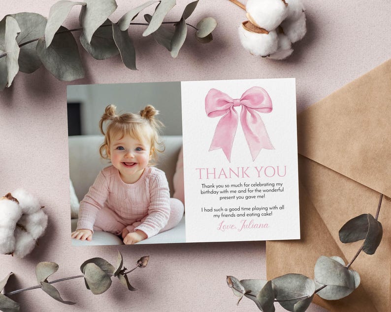 May include: A pink and white thank you card with a watercolor bow illustration. The card features a photo of a smiling baby girl and the text "THANK YOU" with a personal message. Eucalyptus and cotton accents surround the card.