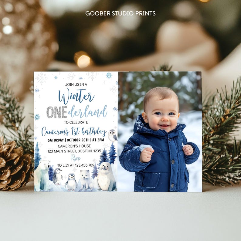 May include: A rectangular birthday invitation card featuring a Winter ONEderland theme with blue snowflakes, arctic animals, and text reading Join us in a Winter ONEderland to celebrate Cameron's 1st birthday, plus a photo of a child in a blue coat.