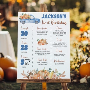 May include: A white birthday milestone sign for Jackson featuring a blue truck, orange pumpkins, and floral accents. The text includes weight, height, favorite foods, songs, toys, and nicknames. It lists 30 pounds, 28 inches, and 5 teeth.