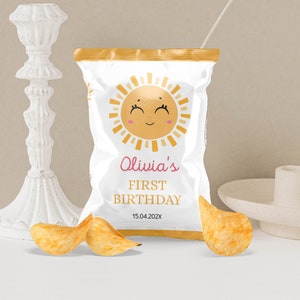 May include: A white bag of chips with a yellow sun design and the text "Olivia's First Birthday 15.04.202X".