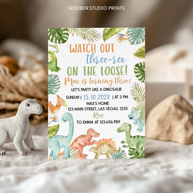 May include: A rectangular birthday invitation card featuring watercolor illustrations of various dinosaurs and tropical leaves. The text reads: WATCH OUT three-rex ON THE LOOSE! Max is turning three! LET'S PARTY LIKE A DINOSAUR SUNDAY | 15.10.202X | AT 3 PM MAX'S HOME 123 MAIN STREET, LAS VEGAS. 1235 RSVP TO EMMA AT 123.456.789.